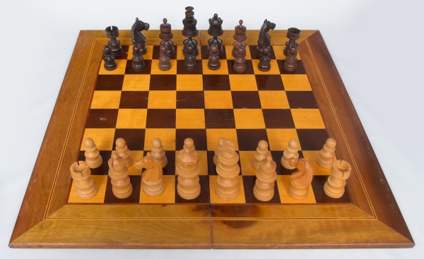 Um tabuleiro de xadrez com um grande pedaço de madeira e uma grande obra de  arte nele