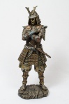 Samurai, estatueta oriental, em material sintético patinado prateado c/ detalhes dourados, alt. 42cm.