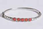 Pulseira escrava, formato oval, em prata com 5 corações em vermelho. Medindo 5 cm internamente. 