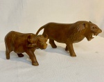 Lote com par de animais em madeira entalhada - Representando Buffalo (Medidas: 12 cm x 6 cm); Leão (19,5 cm x 6 cm). Made in Kenya.
