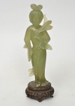 Estatueta esculpida em jade, representando gueixa com flores e leque nas mãos, base de madeira tendo