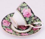 Xícara e pires em porcelana inglesa, decorada com flores e folhas, inspirados em barrados de antigos bordados manuais. Marcada ao fundo Royal Albert, England.