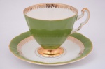 Xícara e pires em porcelana inglesa, face externa da xícara em verde intenso com base dourada. Borda da xícara e do pires em verde e dourado. Marcada Royal Adderle, England.