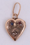 Relicário em ouro, forma de coração, pequenos brilhantes, rubi e safira. Peso bruto 2,4 g. Pequenos amassados.