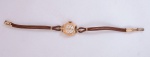 Relógio feminino, mostrador esmaltado, anos 40. Em ouro contrastado 14 quilates, pulseira algodão trançado em excelentes estado de conservação. Acondicionado em caixa original. Funcionando. Peso 9,2 g.