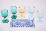 Seis peças: A) Cinco taças para licor em vidro colorido, Altura 8,5 cm; B) Bandeja em porcelana thailand, decorado com pinturas flores e folhagens.Medindo 16,5 x 19 cm.