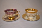 Duas elegantes xícaras em porcelana com pintura em alto relevo e fios de ouro na base e nas bordas. Med: 7 x 12 cm.