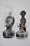 Lote composto de 02 lampiões a querosene, sendo 01 com cúpula translucida, medindo 0,30cm de alt., e 01 lampião sem cúpula
