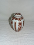 Potiche com tampa em porcelana nacional nas cores branca e marrom com decoração floral e guirlandas. Med.: 19 cm.