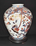 IMARI - Elegante vaso palaciano confeccionado em porcelana oriental com decoração floral colorida e filetado a ouro, acompanha peanha em madeira nobre patinada no tom negro. Med.: 53cm.